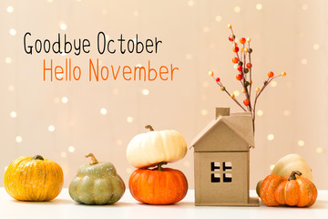 Goodbye October Hello November message with collection of autumn pumpkins with a toy house