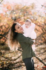 Fototapeta premium Young mother with little girl in autumn forest with a beautiful colored background
