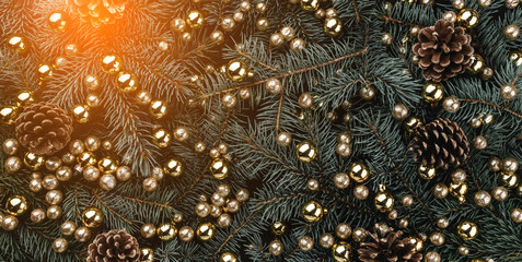 Obraz na płótnie Canvas Winter background of fir branches. Adorned with baubles and golden cones. Christmas card. Top view. Xmas congratulations. Light effect.