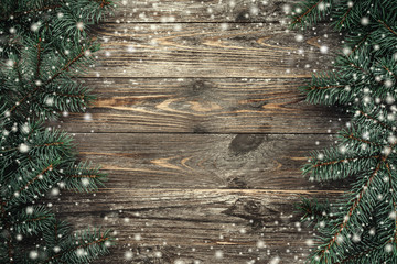 Old wood background with fir branches. Space for a greeting message. Christmas card. Top view. Effect snowflakes.