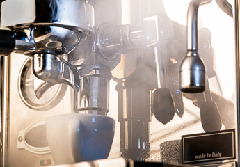 Dramatic photo of an espresso machine producing steam and water vapor; concepts: cafe, coffee, espresso, latte, cappuccino, barista  