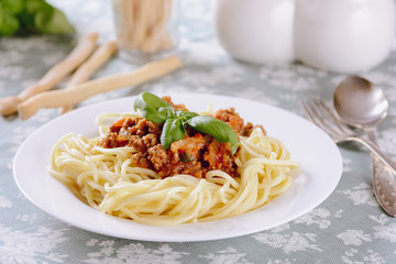 Spaggettes with bolognese sauce in a white plate are on the dining table	