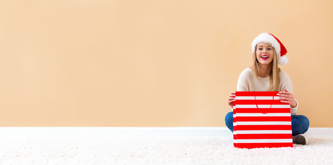 Happy young woman with Santa hat holding a shopping bag