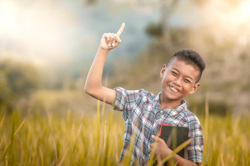 Happy boy standing in rice field. holding bible and saying one way jesus.