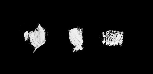 three white abstract paint strokes isolated on black surface isolated f