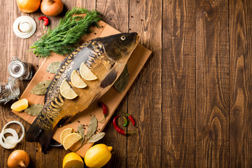 Delicious fresh fish on dark wooden background. Fragrant spices and lemon.