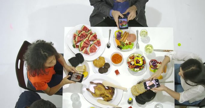 Group of friends at dinner party with all people on the table uses their smartphone for taking photos of dinner food. Instagram, Social network addiction concept.