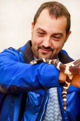 Boy with snakes. Man holds in hands reptile Common King snake Lampropeltis getula kind of snake. Exotic tropical cold-blooded animals, zoo. Pets at home snakes. Poisonous and non poisonous snake.