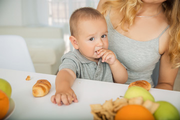 The child eats fruit breakfast at mom's hands