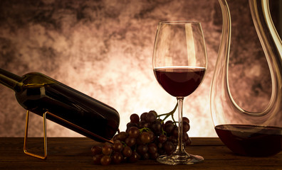 Red wine. Glass of red wine, grapes and decanter on wooden background.