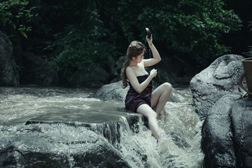 Young asian girl lady sexy and smiling relaxation sit bathing in a natural forest waterfall 
