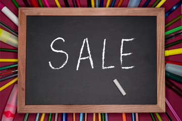 SALE written on chalkboard on purple background with stationery