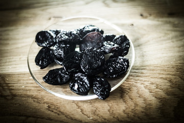closeup.prunes in a bowl and muesli on a wooden table