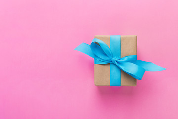 gift wrapped and decorated with blue bow on pink background with copy space. Flat lay, top view