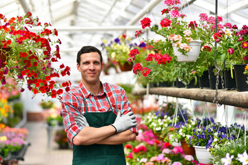 smiling gardener at work in a greenhouse // Portrait lächelnder gärtner bei der Arbeit im...