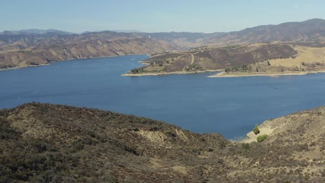 A blue lake in between hills with power boats and kayaks
