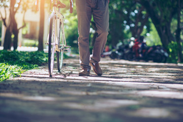 Save energy concept.Cycling is a way to save energy and protect the clean environment.Leg of Asian men walking with bicycles in green park,to work and exercise in the morning.