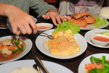 Boys  hand scooping Telur bungkus  or wrapped egg on plate over dining table