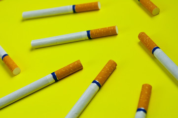 Lot of cigarettes with tobacco and filter scattered on yellow background. Stop smoking concept