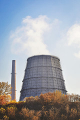 Pipes of a thermal power plant with steam against background of blue sky