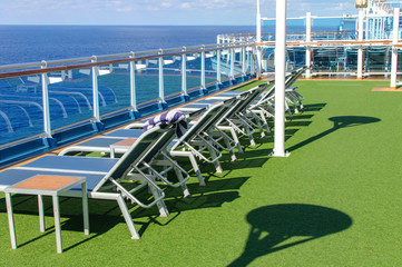 View from the deck of a cruise ship in the ocean. Seating area for passengers, chairs and sun loungers. Sunbathe.