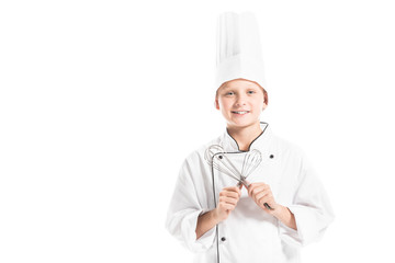portrait of smiling pre-adolescent boy in chef uniform and hat with whisks isolated on white