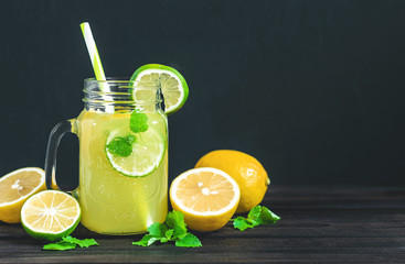 Lemonade drink of soda water, citrus and mint on the dark background. Cocktail glass with handle...