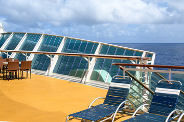 View from the deck of a cruise ship in the ocean. Seating area for passengers, chairs and sun loungers. Sunbathe.