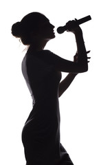 silhouette of girl singing into microphone, profile of young woman face performing lyric song on...