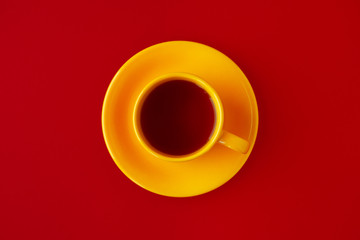 Yellow cup of tea on a red background. View from above. Design in the form of a yellow cup of tea on the middle of a red background. The contrast is red and yellow.