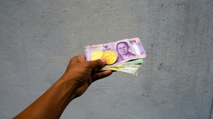 Holding  Bitcoin coin with Thai currency to the wall, Concept Digital money prices fluctuate, Thailand is difficult to control like a barrier wall Digital money.
