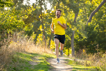 Athletic young man running in the nature at sunset in autumn in fitness Healthy lifestyle