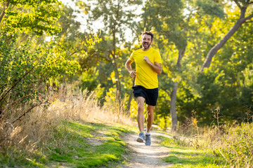 Athletic young man running in the nature at sunset in autumn in fitness Healthy lifestyle