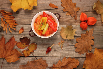 Hungarian Lecso - pepper and tomato stew with autumn leaves and physalis on wooden background
