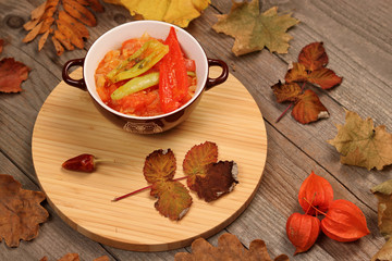 Hungarian Lecso - pepper and tomato stew with autumn leaves and physalis on wooden background