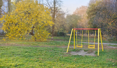 Autumn in the city. Yellowed trees around a playground in the front yard of an apartment building. Kyiv. Ukraine.