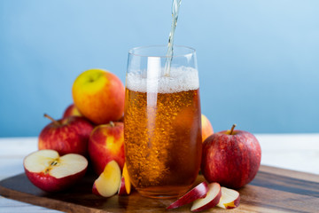 Fresh apple juice in the glass on wooden floor.