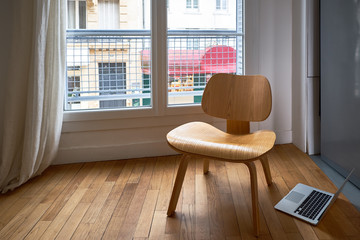 The window of an empty room with an armchair and a laptop overlooks the European street with...