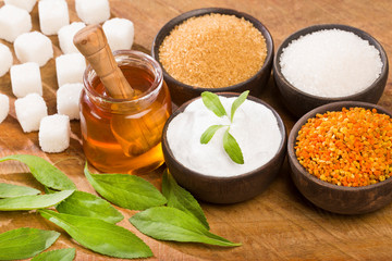 Fototapeta na wymiar Variety of sweeteners - Stevia, sugar, pollen and honey. Wood background