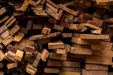 Industrial timber for construction. Old wood used to translate the picture. piled stack of natural brown uneven rough wooden boards lit.