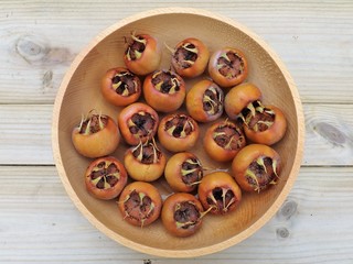 Close-up of fruit of Common medlar Mespilus germanica in a wooden bowl