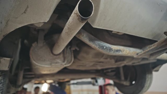 From below view of old rusty car exhaust box in garage during work
