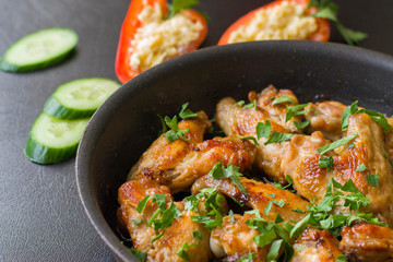Fried chicken wings on the pan and orange paprika with grated cheese and green cucumber.