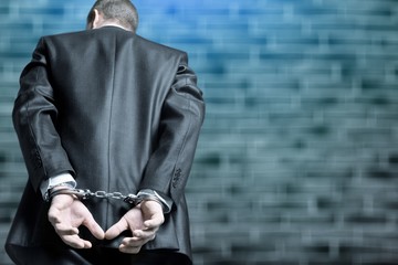 Cropped image of male hands in handcuffs behind his back