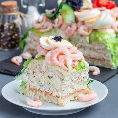Piece of traditional savory swedish sandwich cake Smorgastorta with bread, shrimps, eggs, caviar, dill, mayonnaise, cucumber and lettuce, square format