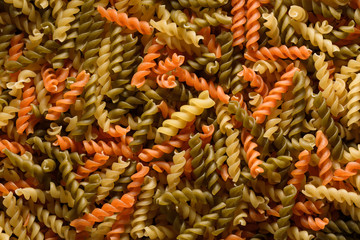 Close-up of raw and colorful fusilli pasta, a decorated pattern background