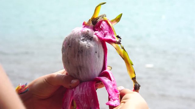 Woman hands clean dragon fruit, ocean background