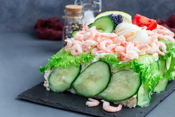 Traditional savory swedish sandwich cake Smorgastorta with bread, shrimps, eggs, caviar, dill, mayonnaise, cucumber and lettuce, vertical, copy space