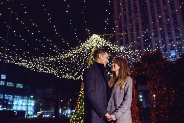 Loving couple at night on the background of street lights in Christmas.