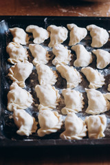 Dumplings raw on a dark board. Traditional homemade food.  Process of cooking dumplings. 